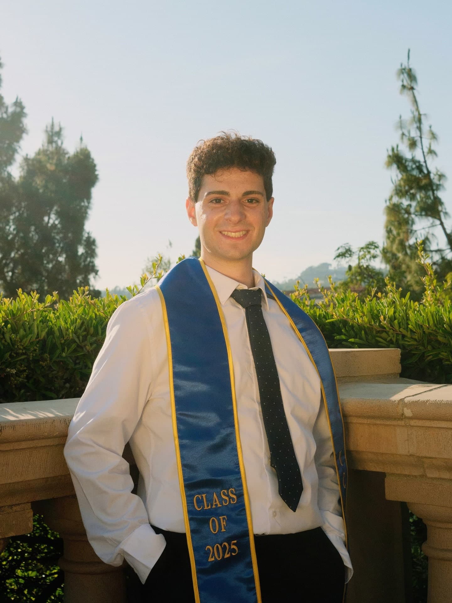 Bassel Lawand, standing outdoors in a UCLA graduation stole
